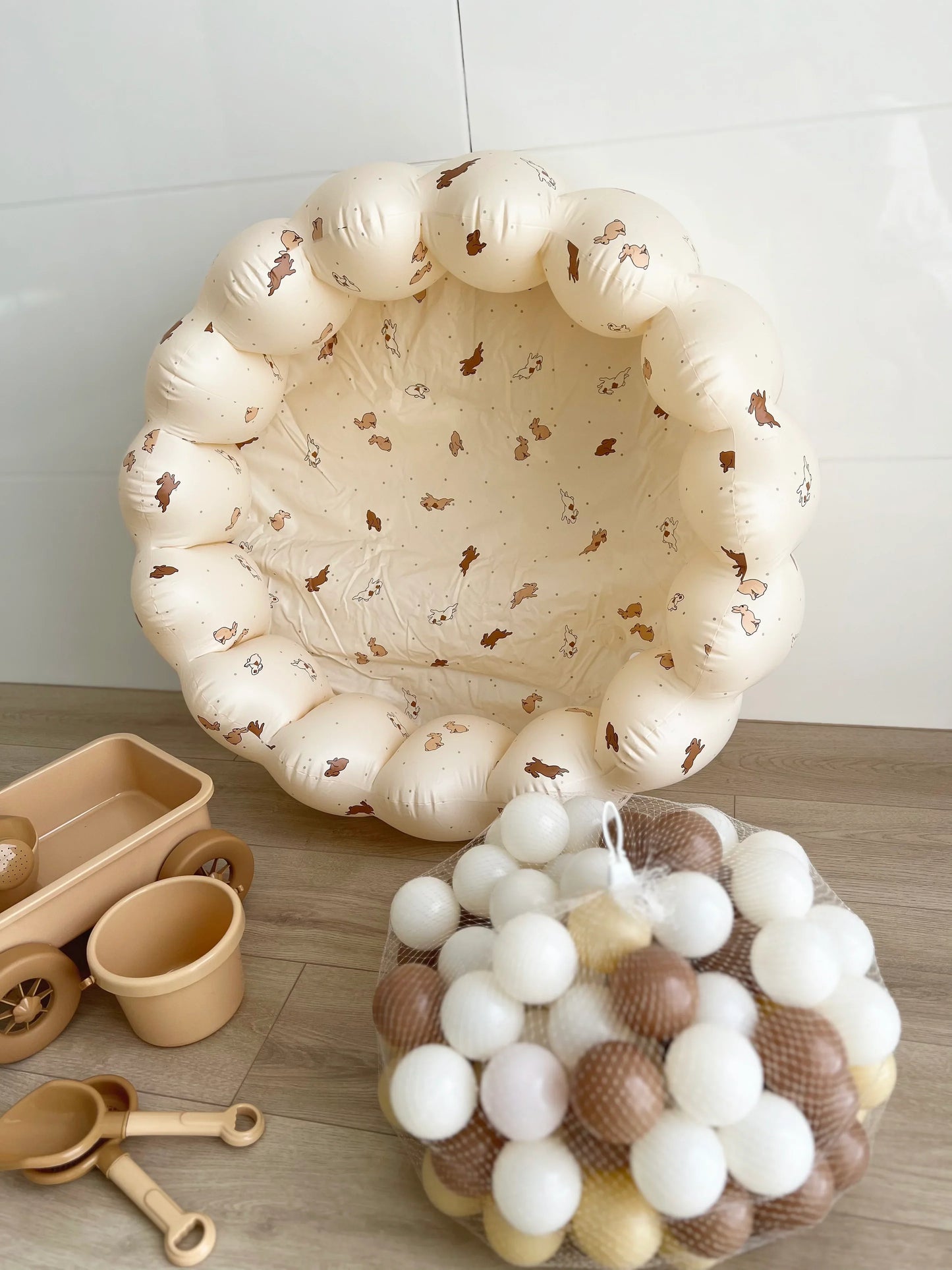 Rabbit petal pool staged against wall with beach toy and balls as play zone