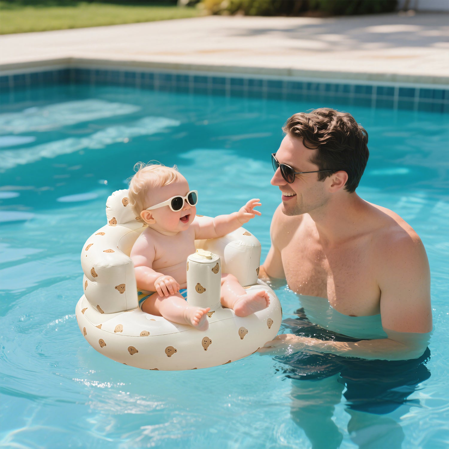 Baby wearing sunglasses enjoys pool time - floating in the ComfyBub™ portable inflatable baby seat with dad